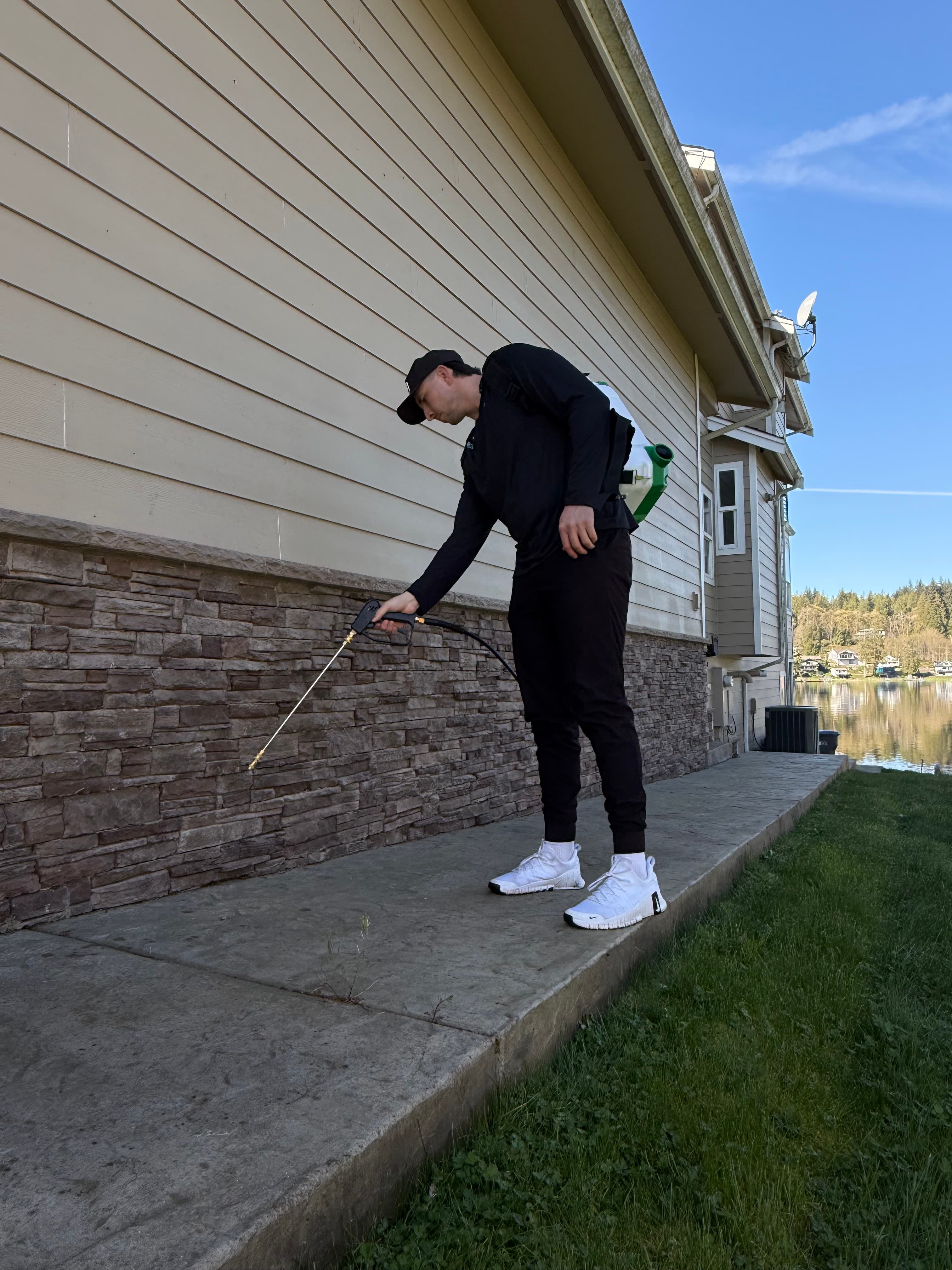 Technician applying perimeter treatment along siding