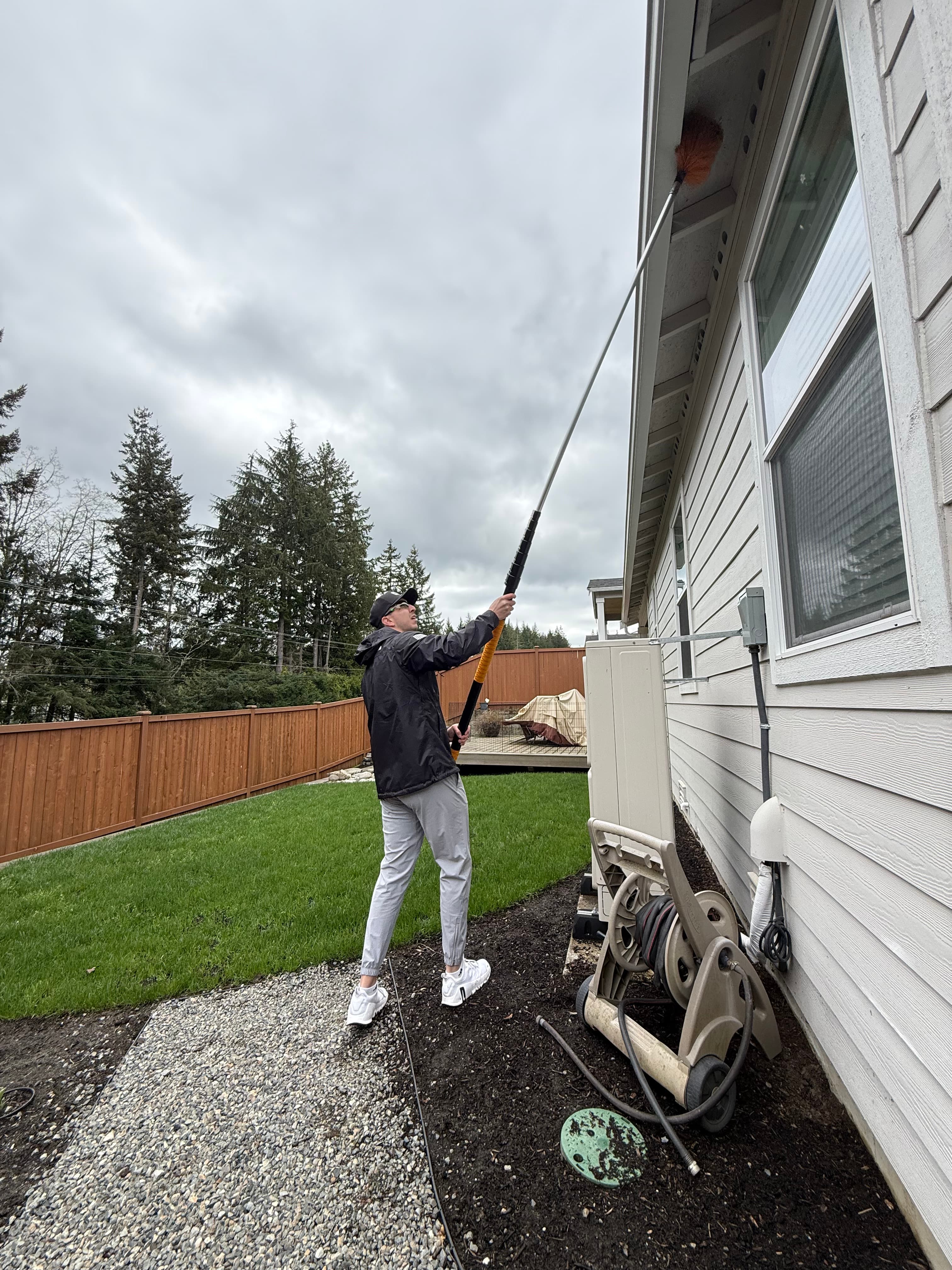 Technician using extension pole to reach eaves and remove nests